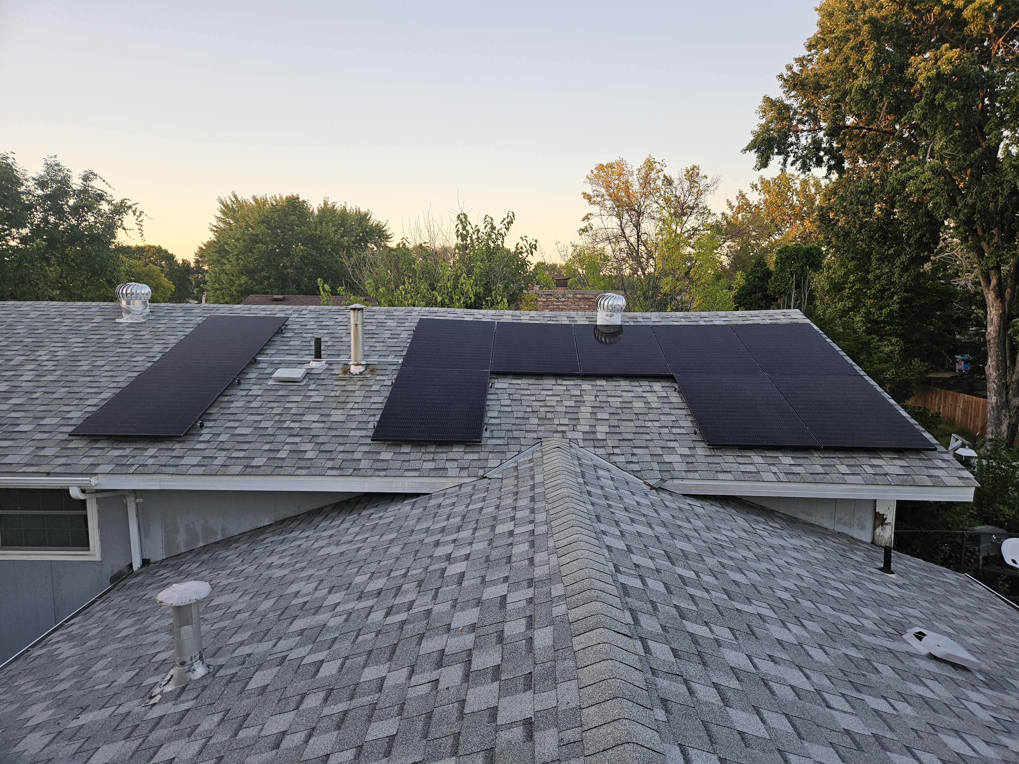 Solar panels installed on a roof with a sunset in the background